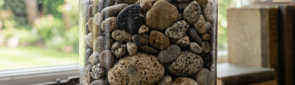 Glass jar filled with smooth river stones on a wooden table